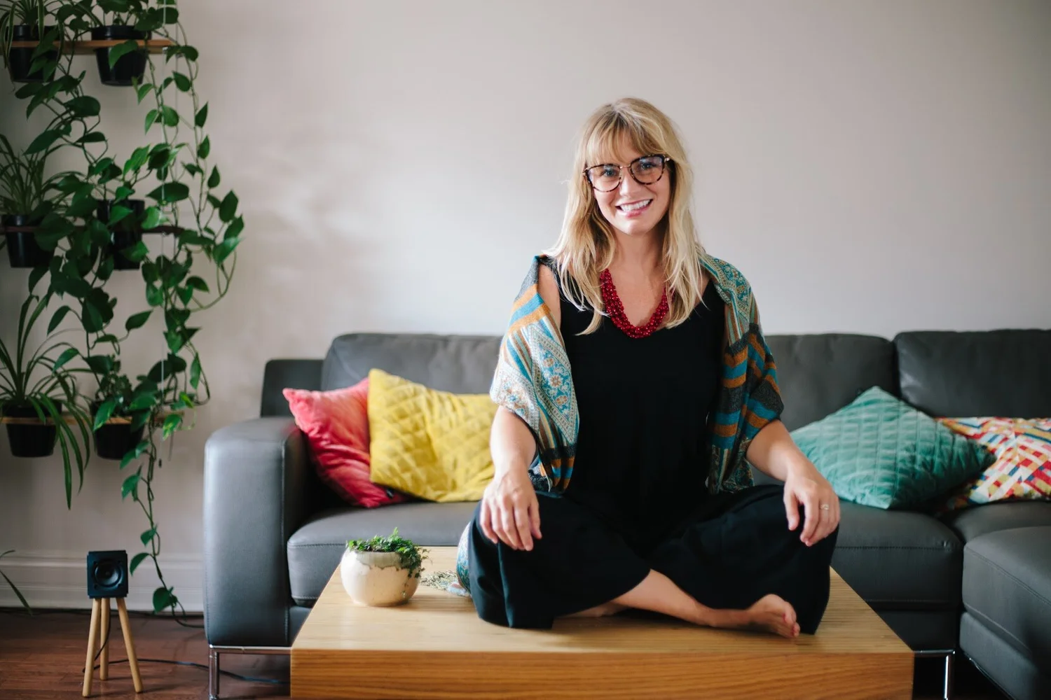 Portrait of Sam sitting cross-legged on a wooden table in front of a sofa