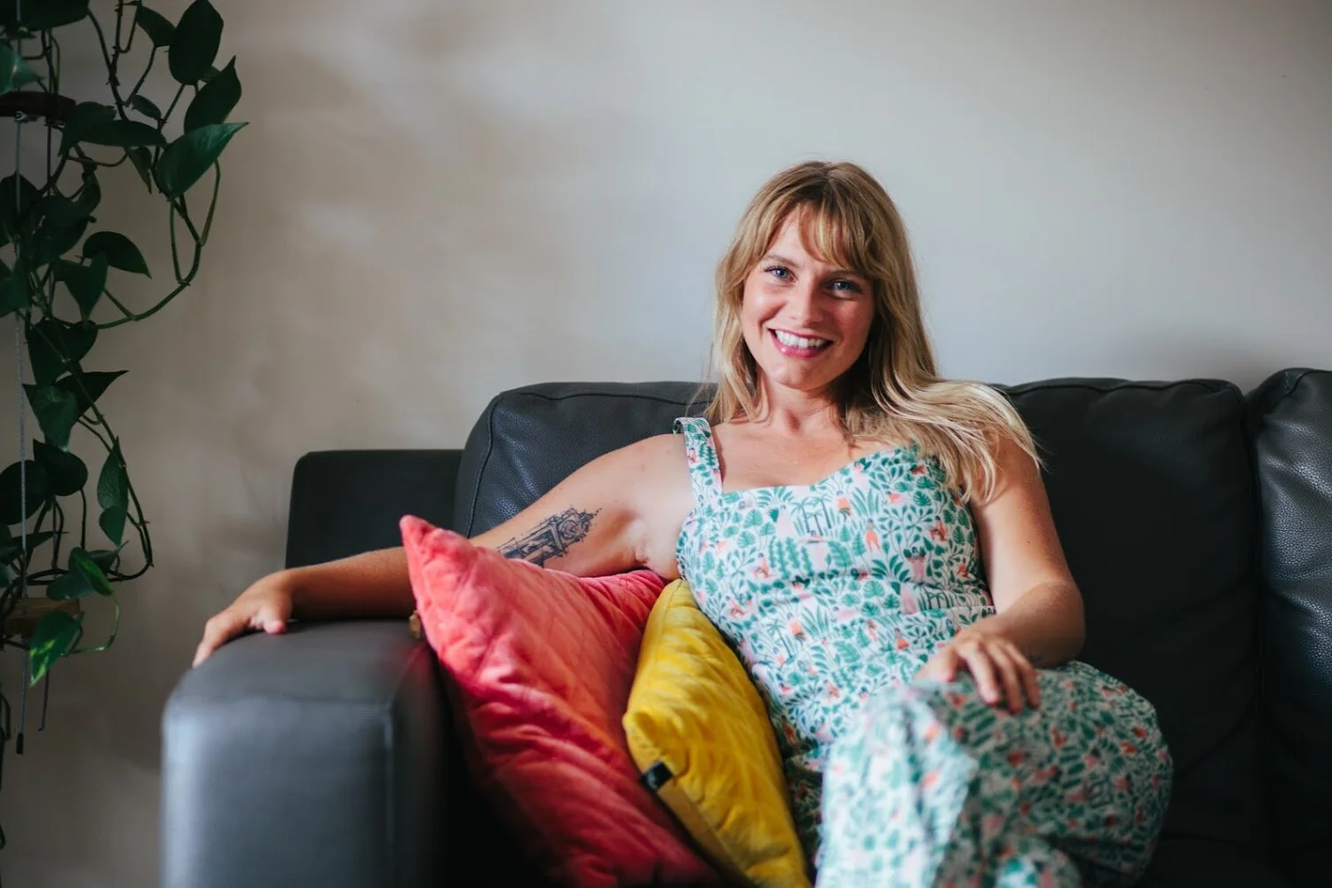 Sam smiling on a sofa with colourful cushions