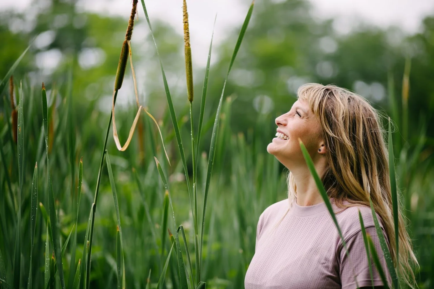 Sam smiling up at tall cattails in a green marsh